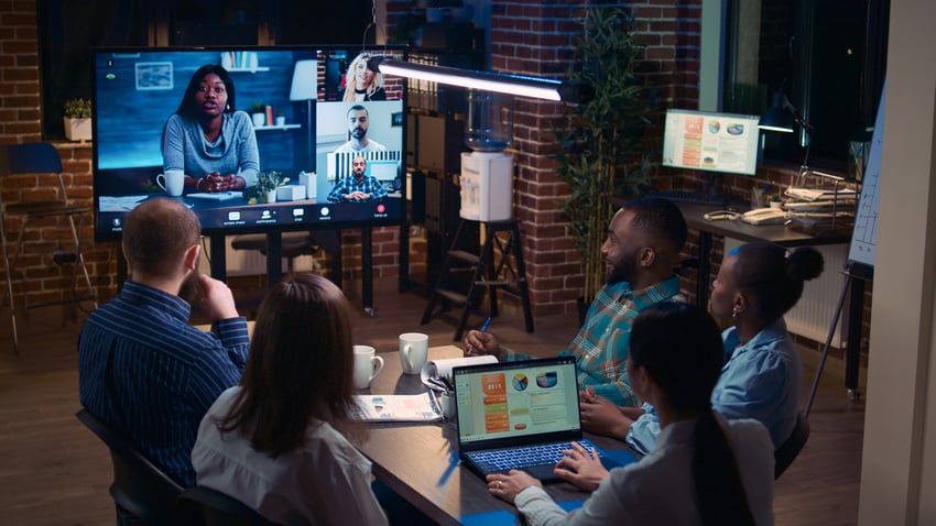 Team meeting occurring in a conference room with a few people dialed in