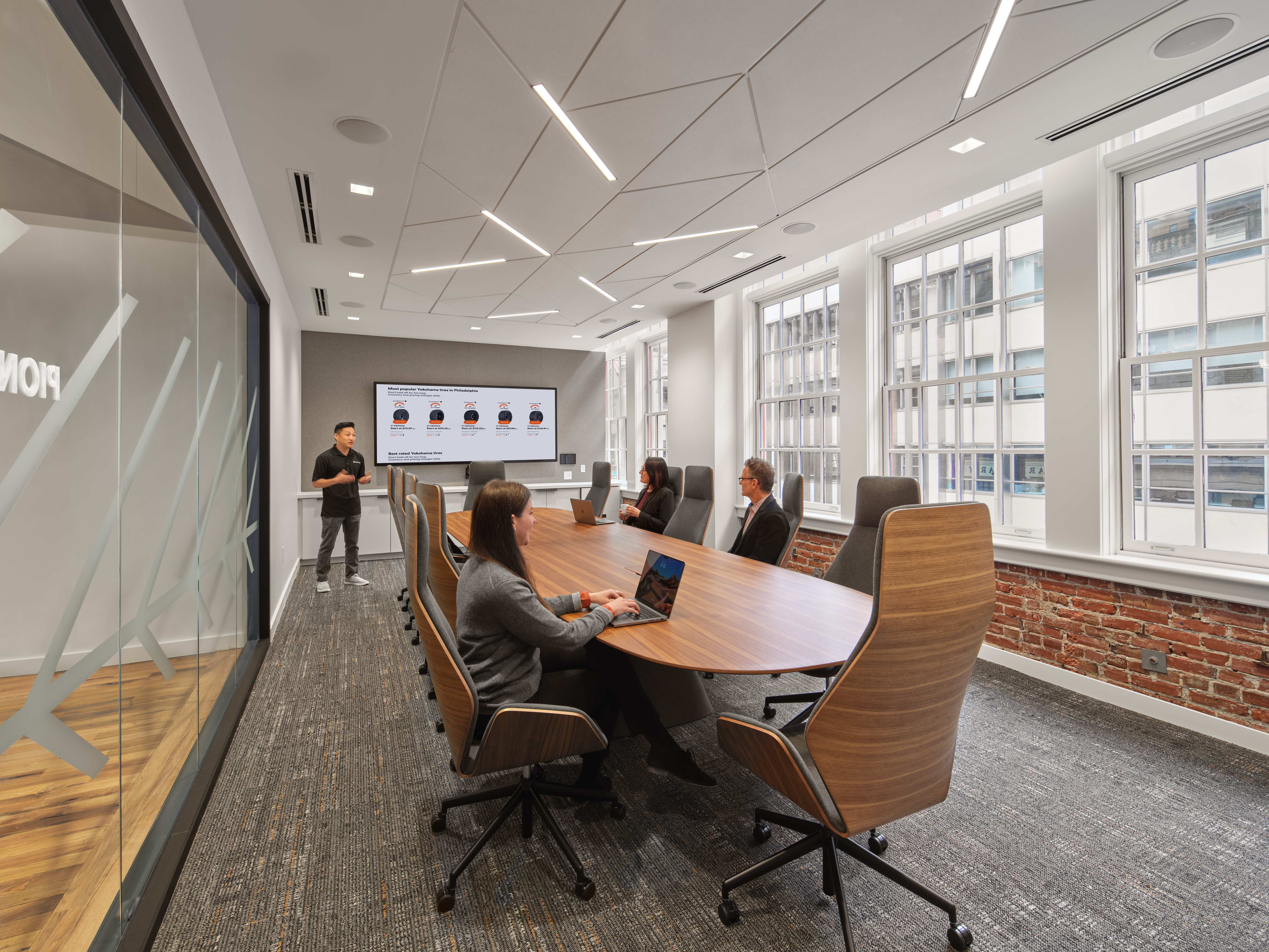 Man giving a presentation on the main screen in a conference room with his peers at the table 